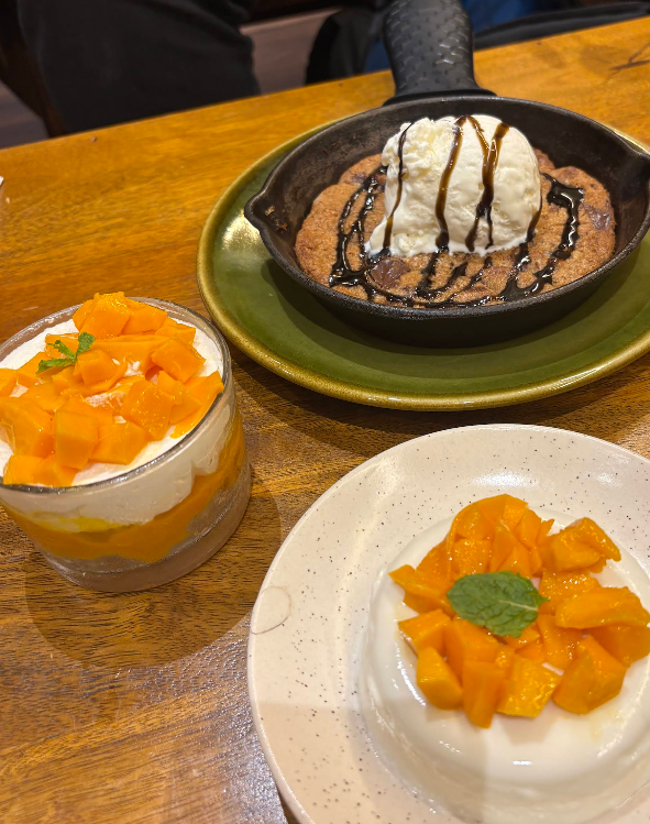 Signature desserts at The Pluvian — skillet cookie with ice cream, mango panna cotta, and mango trifle